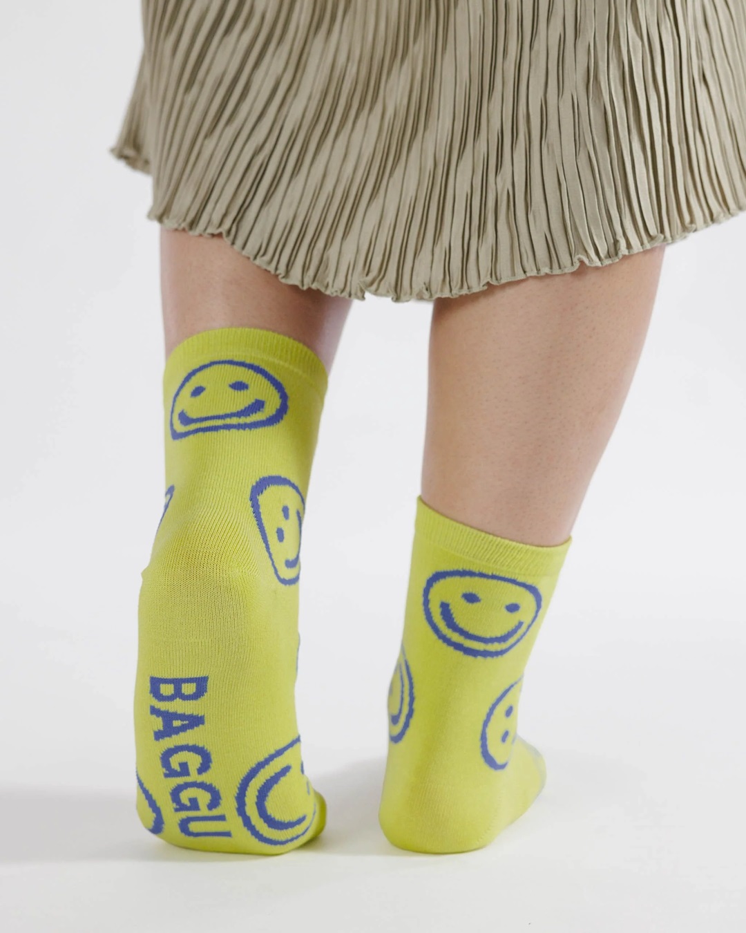 Yellow with blue smiley faces pair of socks on feet