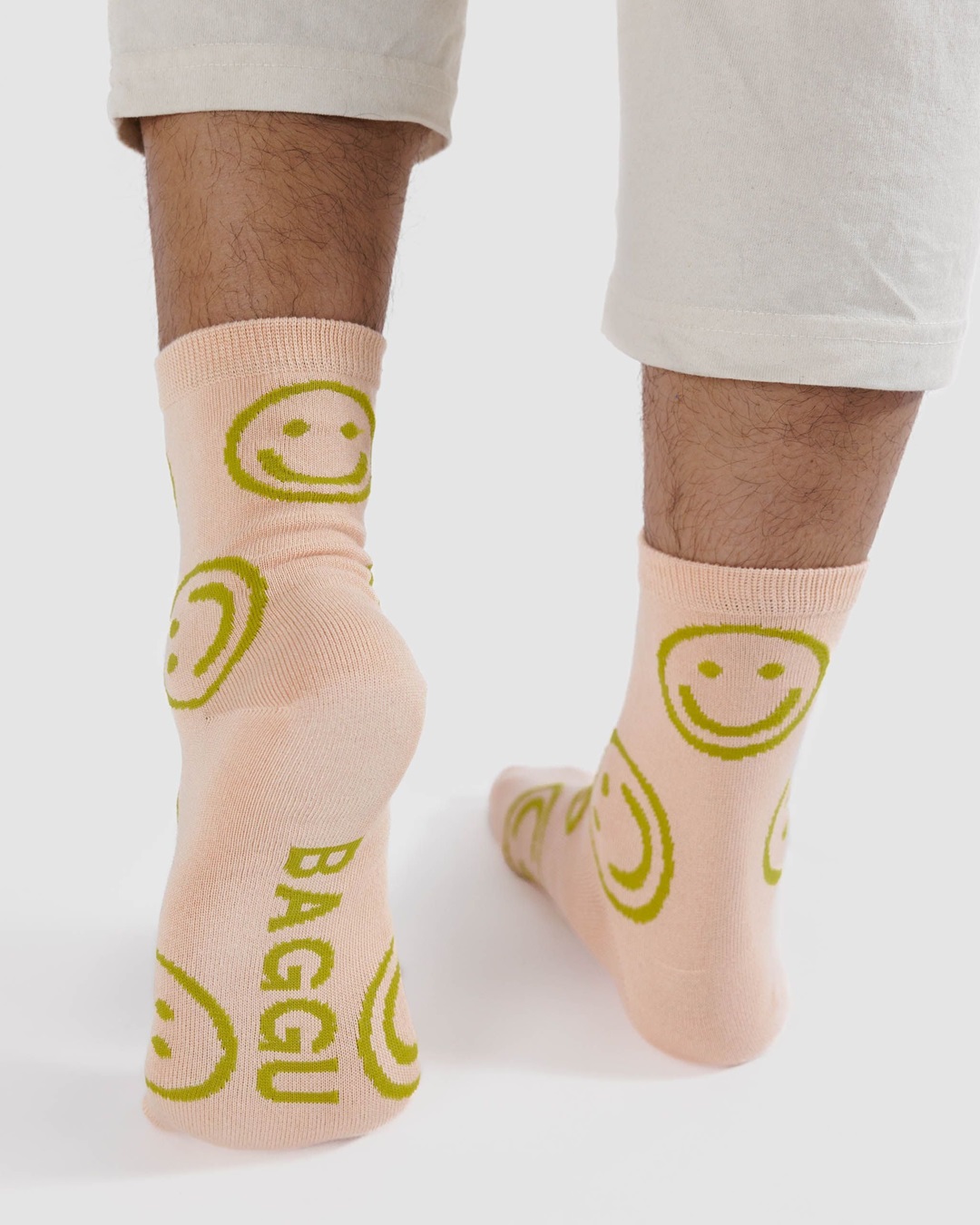 Light pink with green smiley faces pair of socks on feet