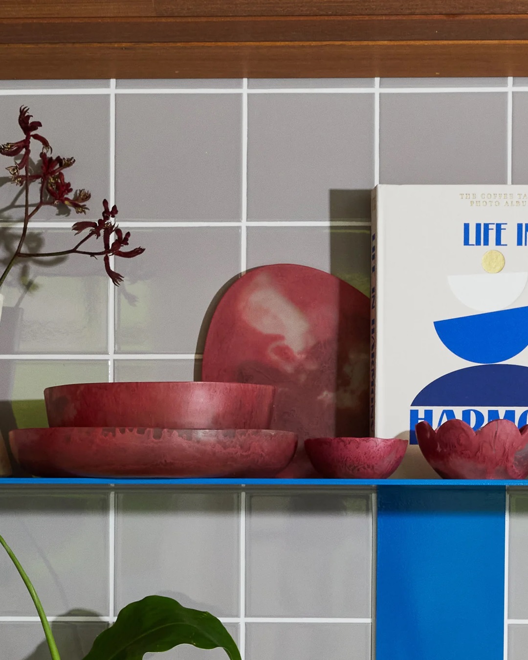 red board on blue shelf with other red bowls