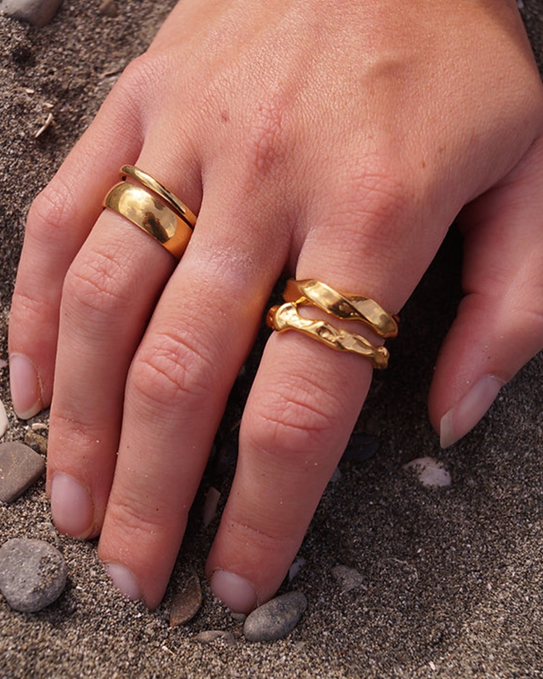 Gold rings on hand in sand