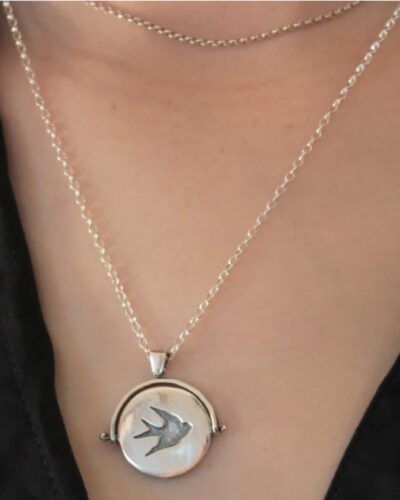 Silver flip circle pendant necklace with a bird on persons neck