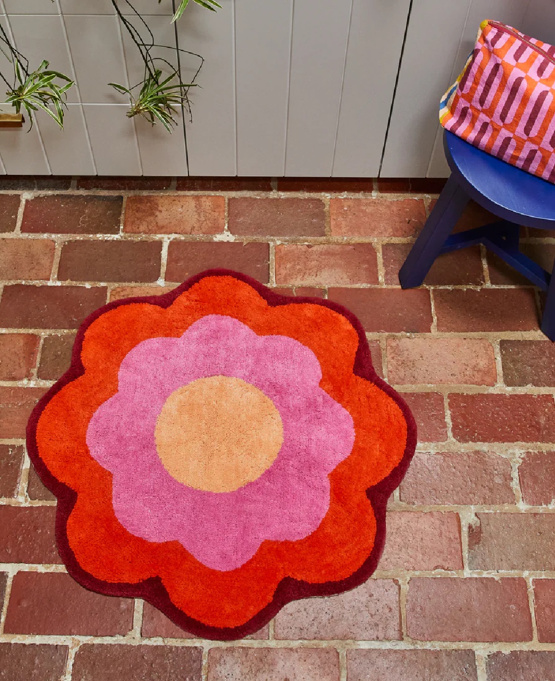 Orange, pink and yellow flower bath mat on brick floor
