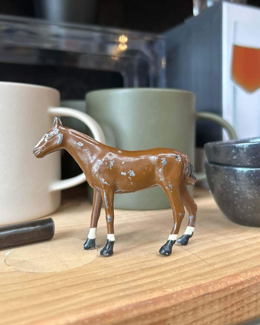 Miniature metal horse with white socks on wooden shelf