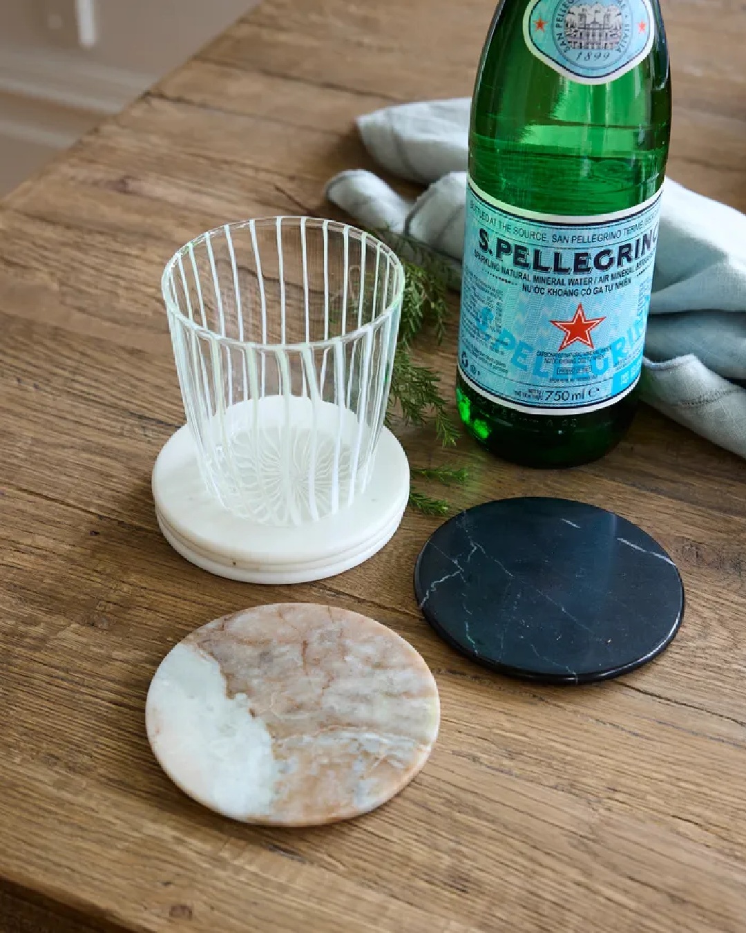 White stripe clear tumbler glass on coaster with water bottle