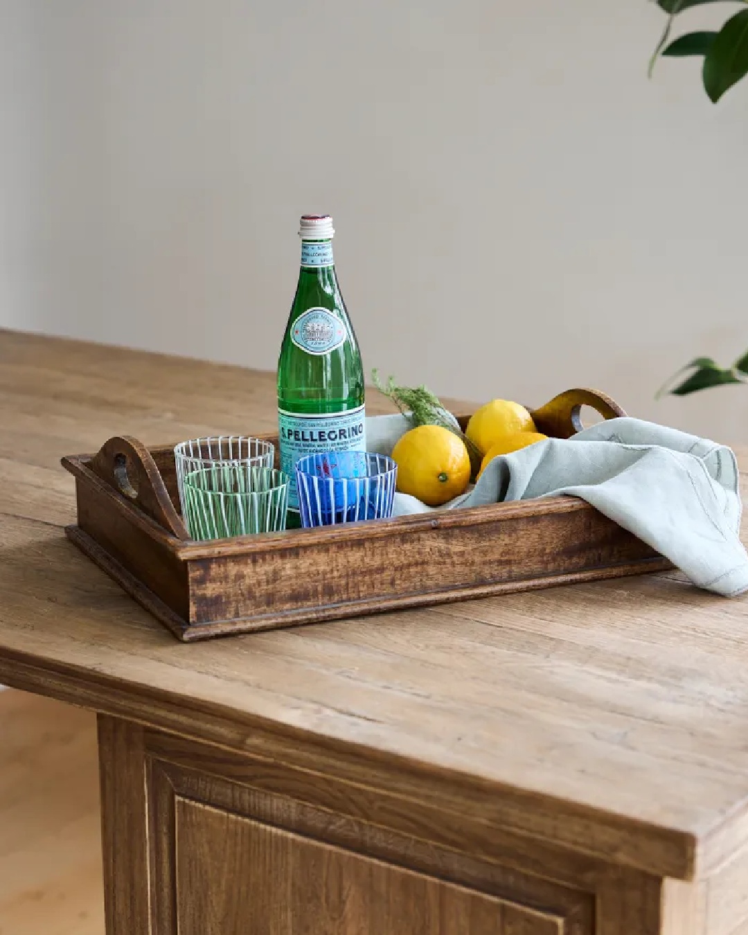 white and green stripe clear tumbler glass on tray with lemons and water bottle