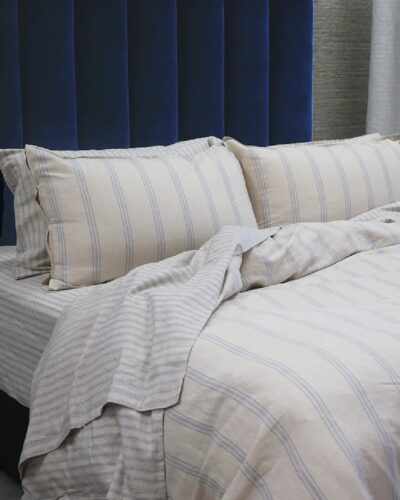 Striped blue and white sheets and duvet on bed with pillows