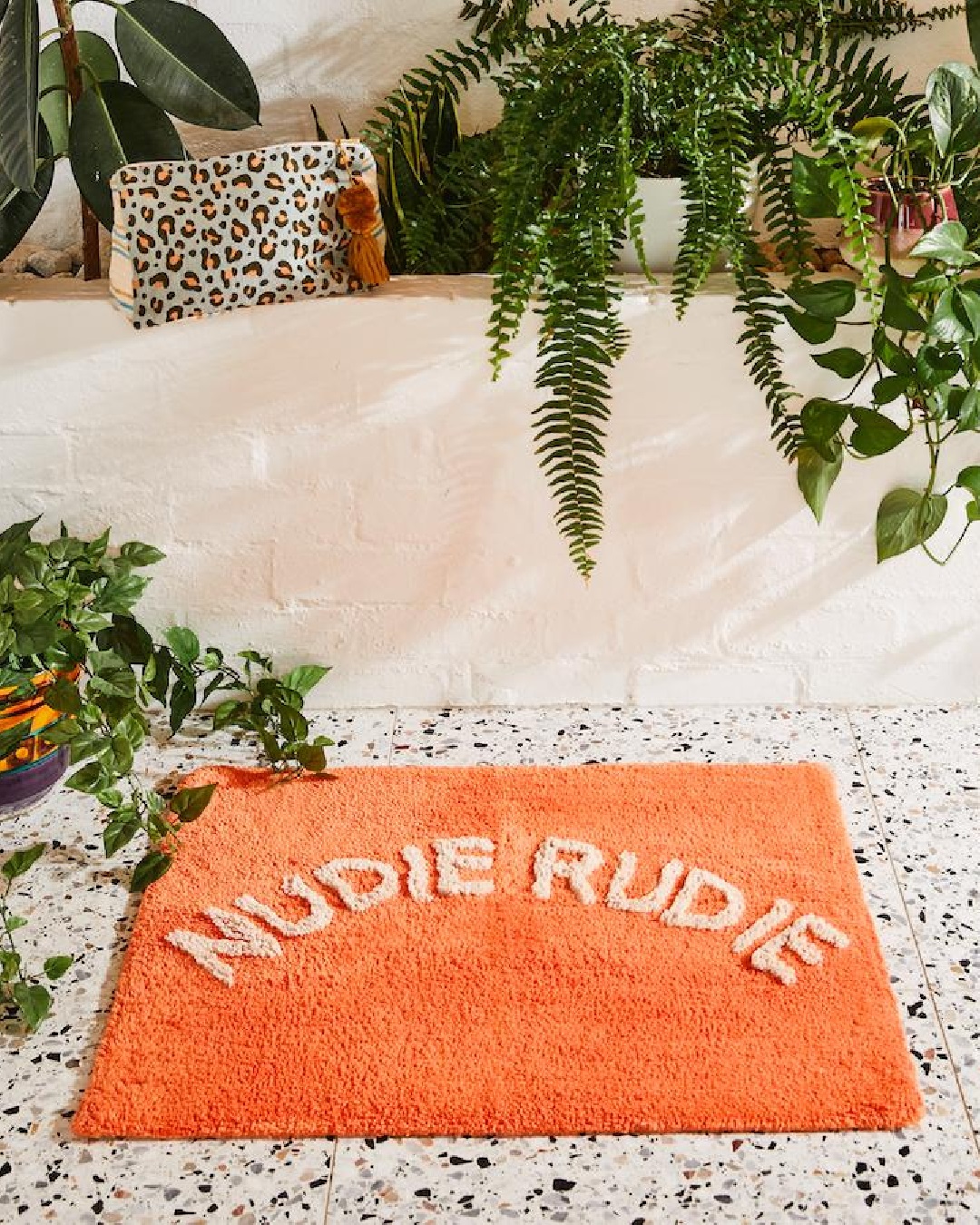 Orange Nudie Rudie bath mat in bathroom on floor