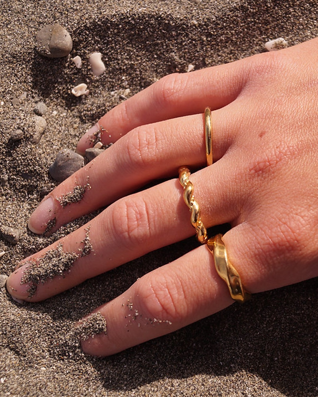 Gold rings on hand in sand