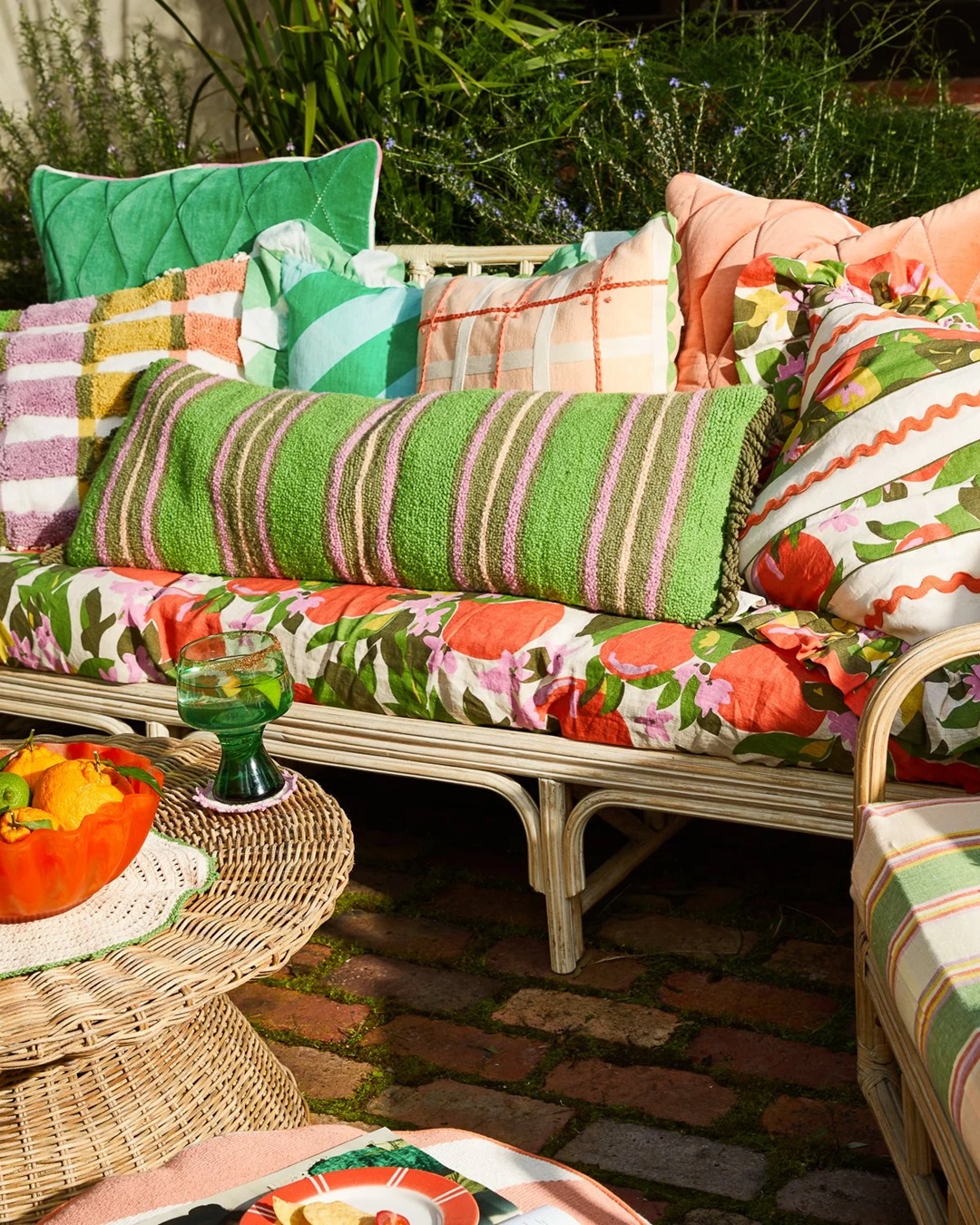 Green and pink stripe rectangle cushion with fringe on chair with other cushions and blanket