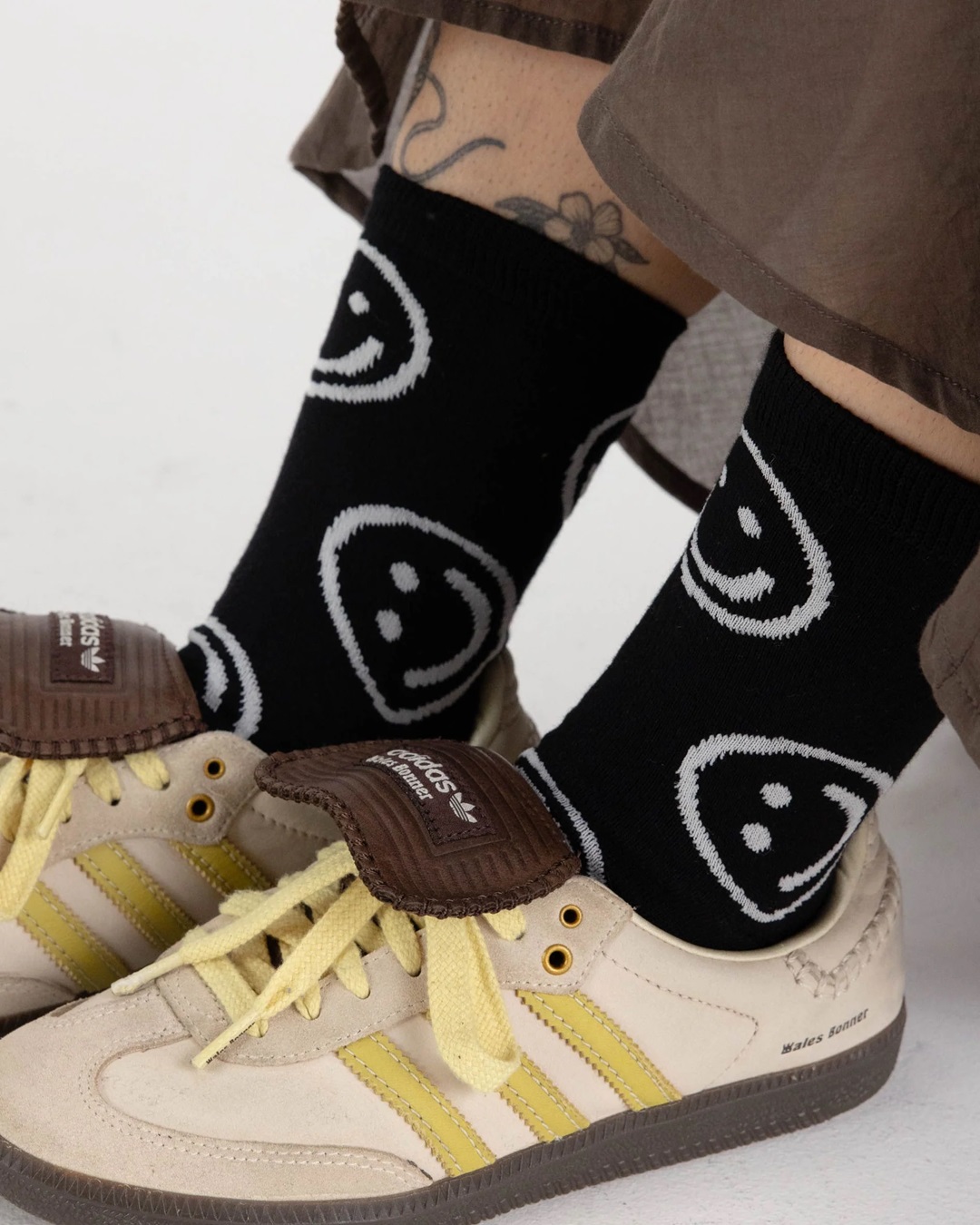 black socks with with smiley faces on someone's feet in brown shoes