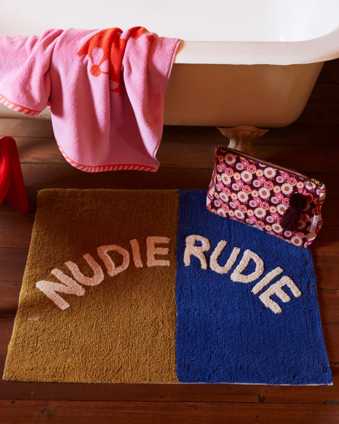 Blue and green Nudie rudie bath mat in front of bath on wooden floor