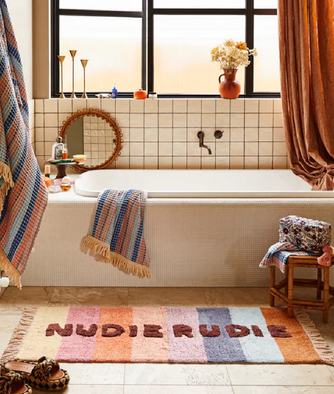 Nudie Rudie bathroom runner with multi coloured stripes and tassels next to bath