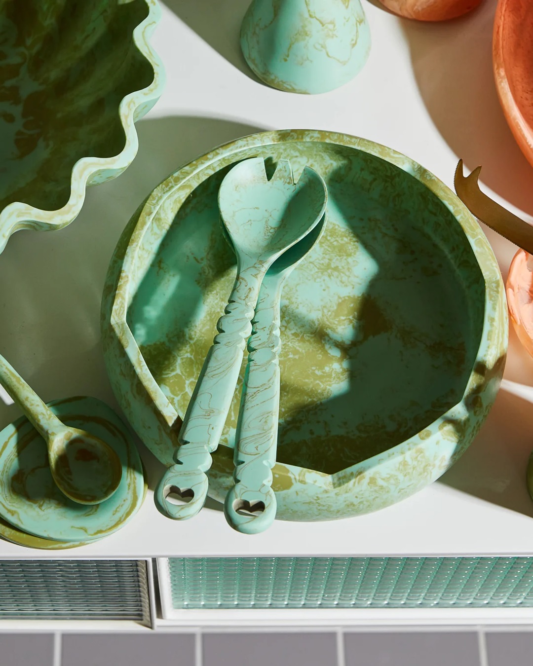 green resin salad servers in bowl on bench
