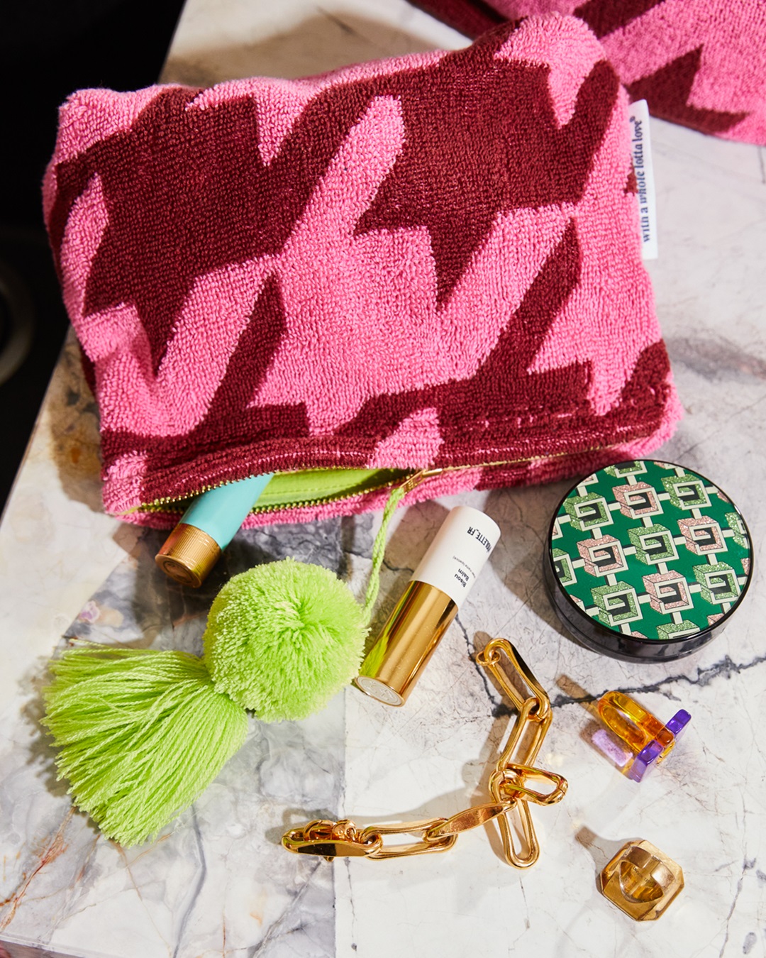 Pink pouch with green pom pom on bathroom bench