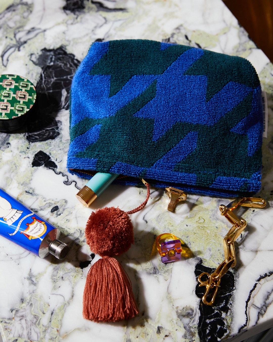 Blue and green pouch with brown pom pom on bathroom bench